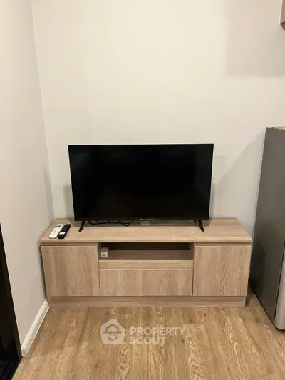 Modern living room with sleek TV stand and flat-screen TV, showcasing minimalist design and wooden flooring.