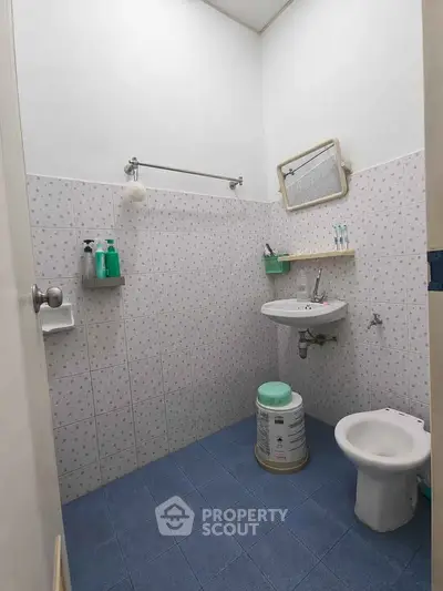 Compact bathroom with tiled walls and floor, featuring a sink, mirror, and bidet for efficient use of space.