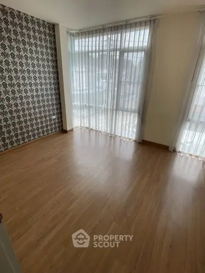 Spacious empty room with large windows and elegant wallpaper, perfect for customization.