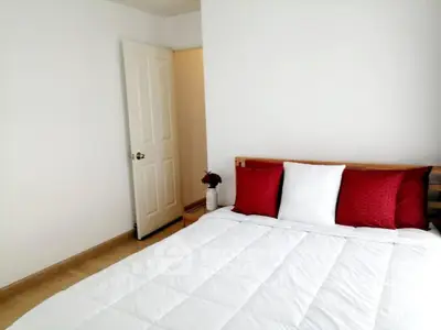 Cozy minimalist bedroom with white bedding and red accent pillows
