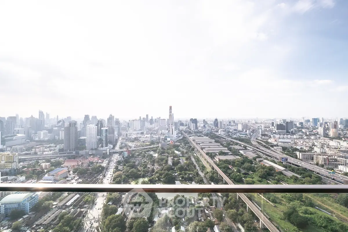 Stunning panoramic cityscape view from a high-rise balcony, showcasing urban skyline and greenery.