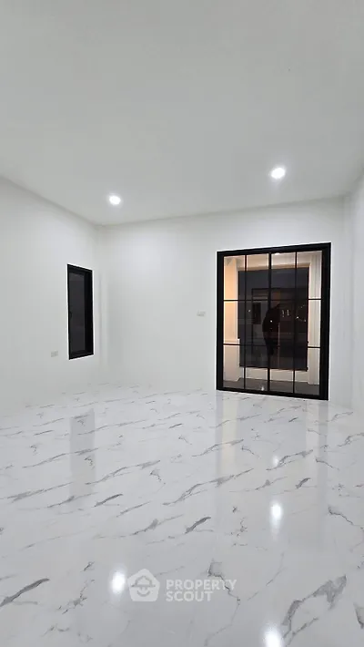 Spacious modern living room with marble flooring and large windows for natural light.