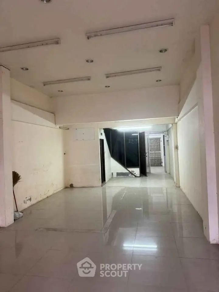 Spacious empty room with tiled flooring and fluorescent lighting, ideal for customization.