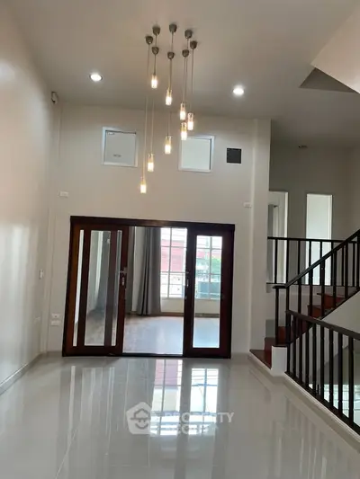 Spacious modern living room with elegant lighting and wooden staircase