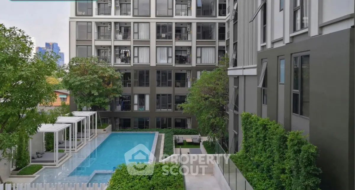 Modern apartment complex with pool and lush greenery, offering a serene urban living experience.