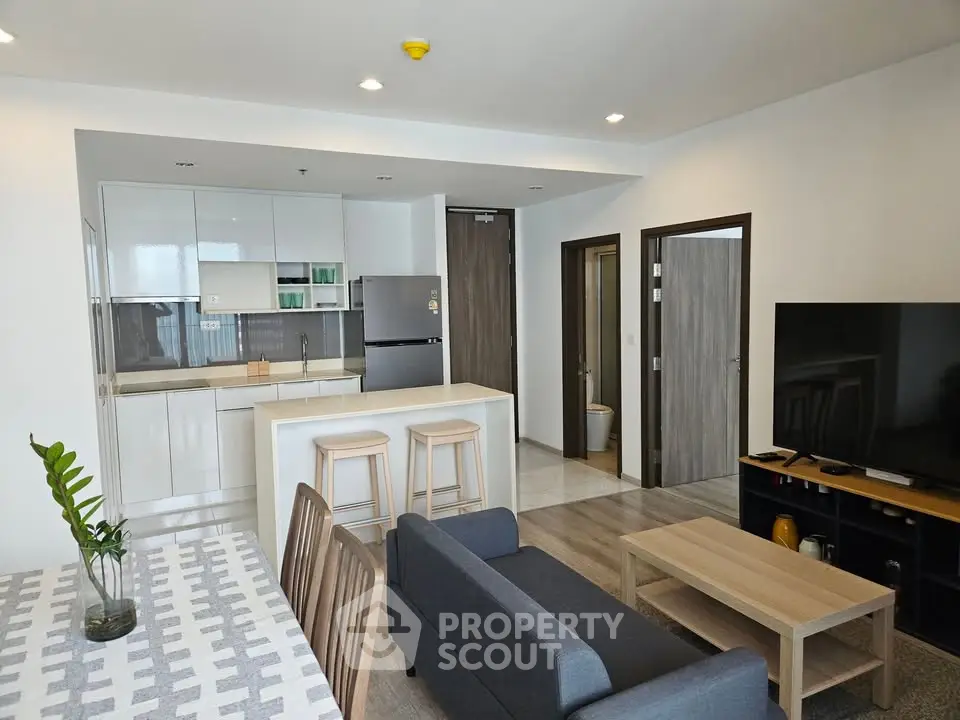 Modern open-plan living room with sleek kitchen and stylish furniture in a contemporary apartment.