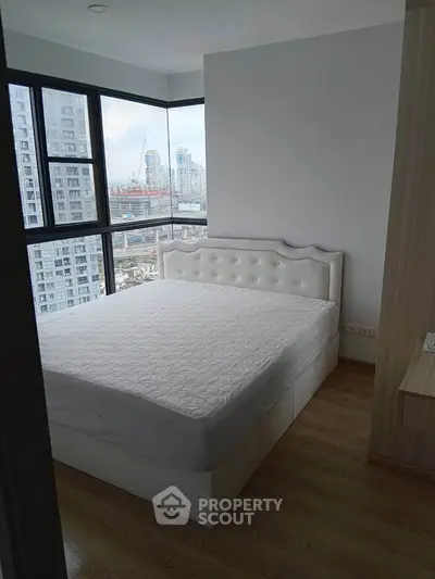 Modern bedroom with large windows offering stunning city views in a high-rise apartment.