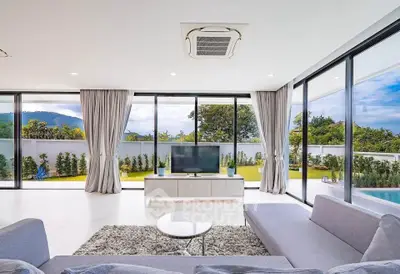 Luxurious living room with panoramic garden and pool view, modern furniture, and abundant natural light.