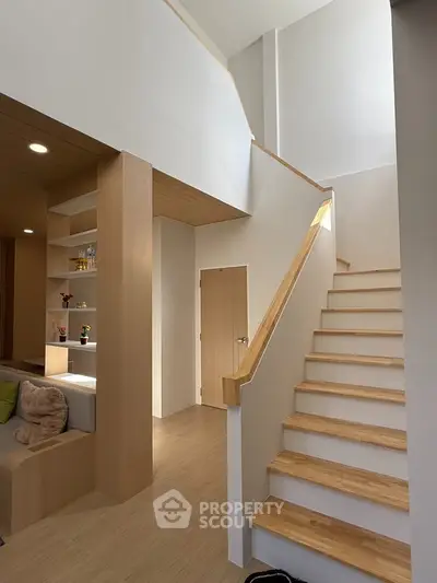 Modern interior with wooden staircase and cozy living area, featuring sleek design and natural light.