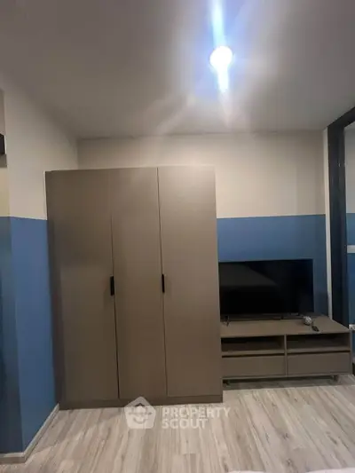Modern bedroom with sleek wardrobe and TV unit, featuring stylish blue accent wall.