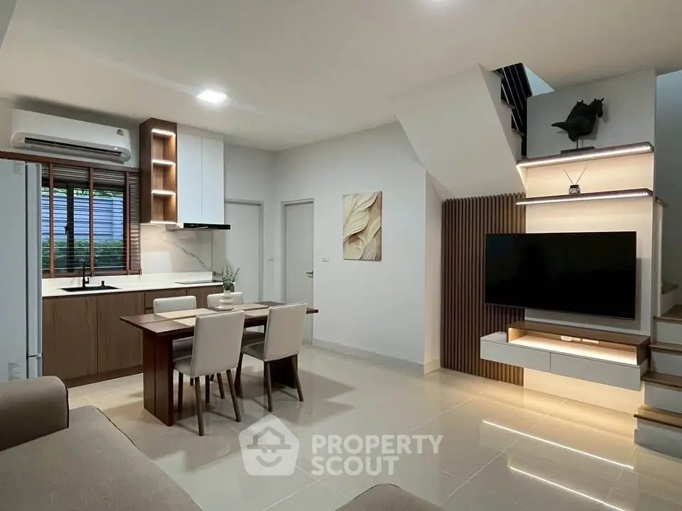 Modern open-plan living room with sleek kitchen and stylish dining area, featuring contemporary decor and ample lighting.