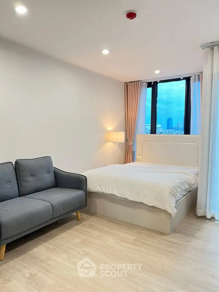 Modern bedroom with city view, featuring cozy bed and stylish sofa, perfect for urban living.