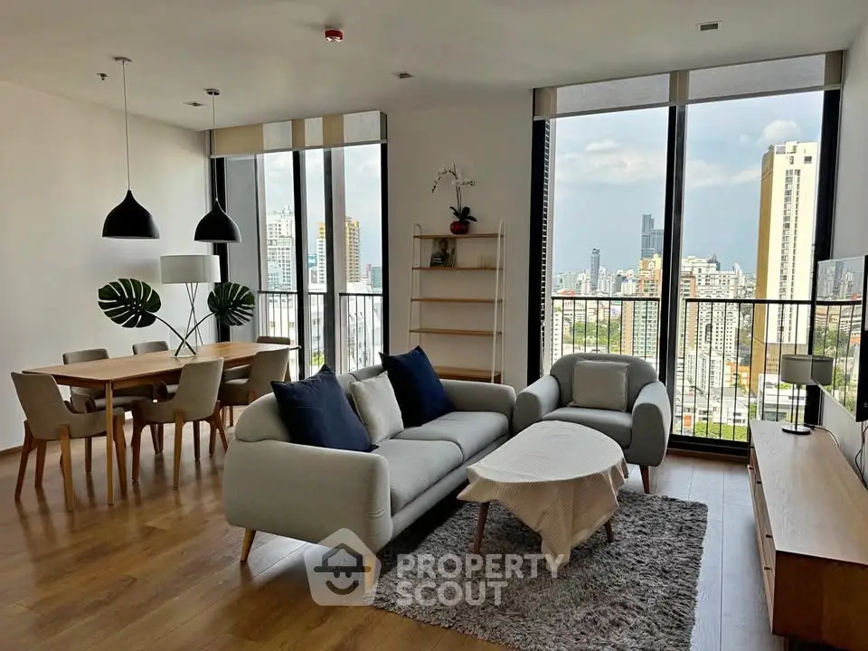 Modern living room with city view, stylish furniture, and dining area in a high-rise apartment.