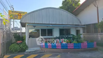 Charming small building with colorful picket fence and lush greenery, perfect for a cozy business or cafe.