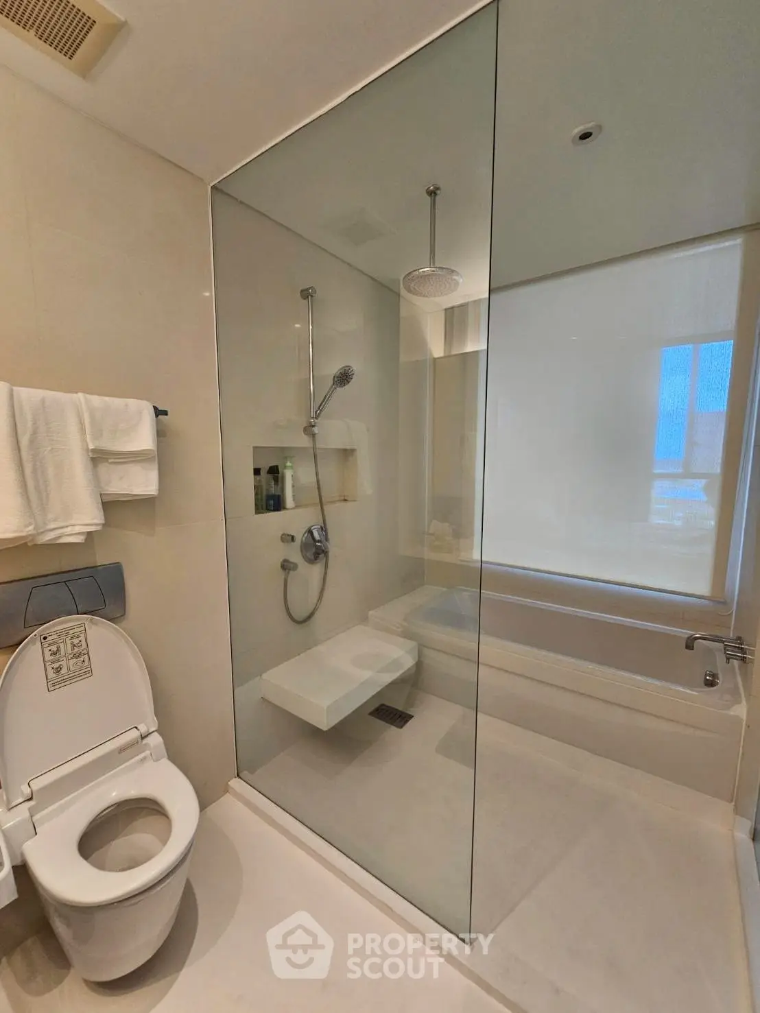 Modern bathroom with glass shower and bathtub in luxury apartment