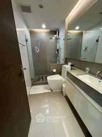 Modern bathroom with sleek fixtures and spacious shower area in a contemporary apartment.