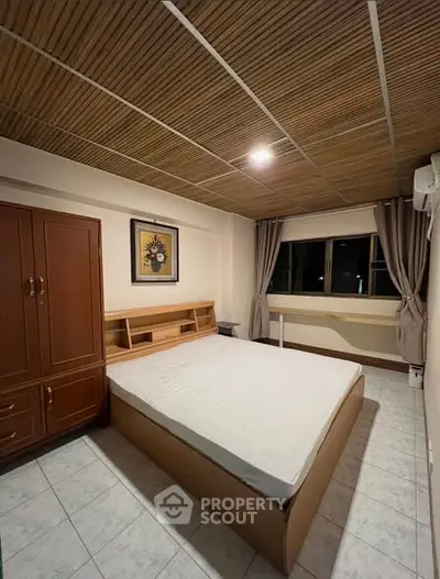 Cozy bedroom with wooden ceiling and large wardrobe in modern apartment