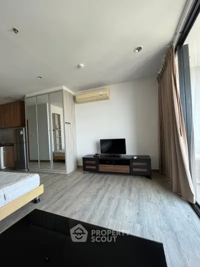 Modern living room with wooden flooring, TV unit, and large mirrored wardrobe