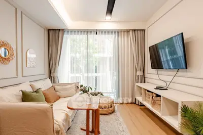 Modern living room with stylish decor, cozy sofa, and wall-mounted TV in a bright apartment.