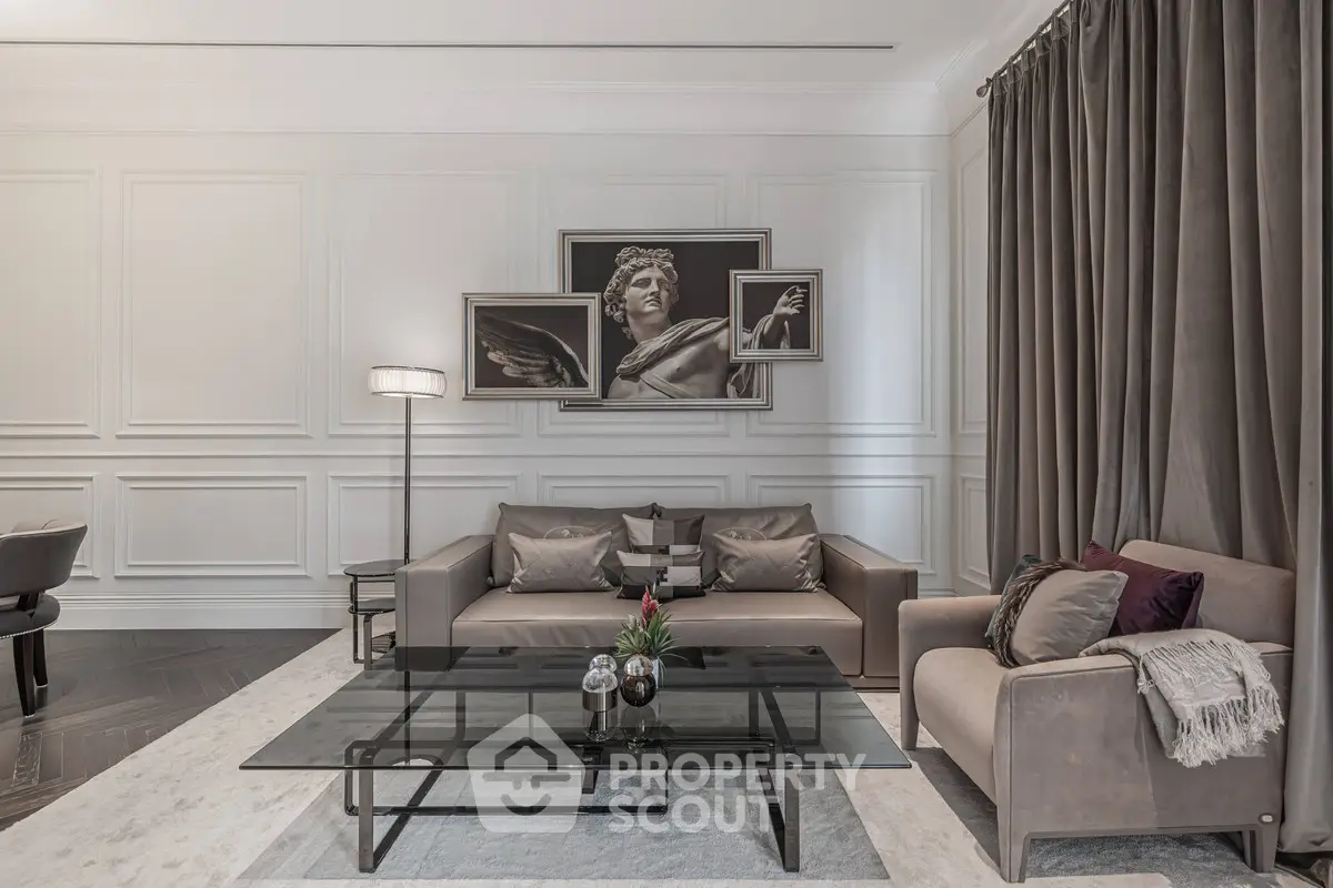 Elegant living room with modern decor and stylish artwork, featuring a glass coffee table and plush seating.