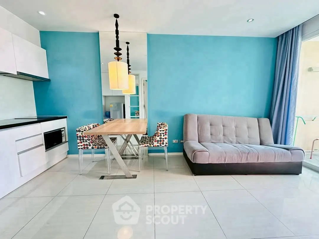 Modern living room with blue accent wall, sleek kitchen, and stylish dining area.