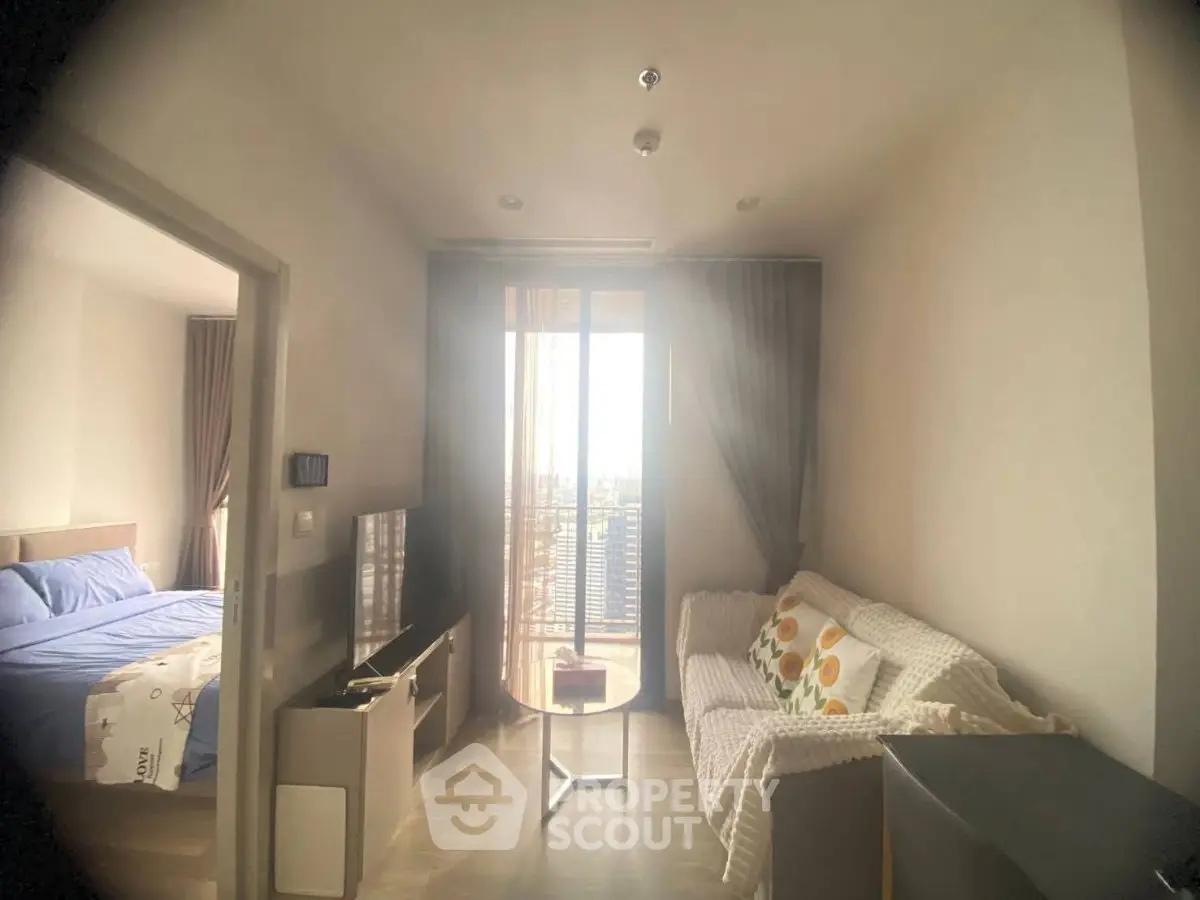 Cozy living room with balcony access and adjacent bedroom in modern apartment.