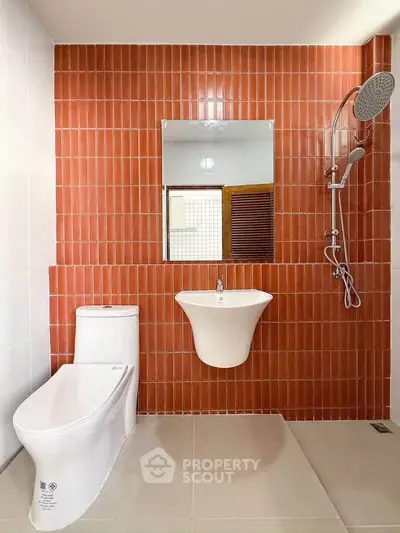 Modern bathroom with red tile accent wall, sleek toilet, and rainfall showerhead.
