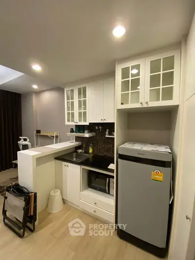 Modern compact kitchen with white cabinets and appliances in cozy apartment
