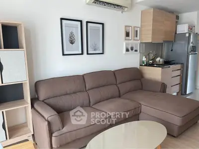 Modern living room with cozy brown sofa and compact kitchen in open layout apartment.