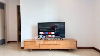 Modern living room with sleek wooden TV stand and flat-screen television.