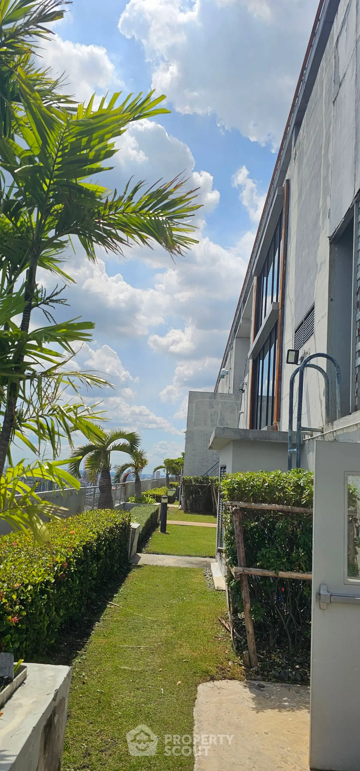 Modern building exterior with lush greenery and clear blue sky