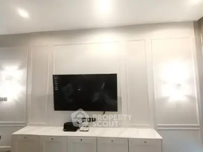 Sleek modern living room with wall-mounted TV and white cabinetry, illuminated by stylish wall sconces.
