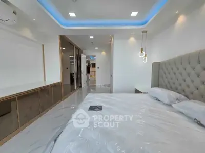 Luxurious modern bedroom with elegant lighting and plush headboard in a sleek apartment.