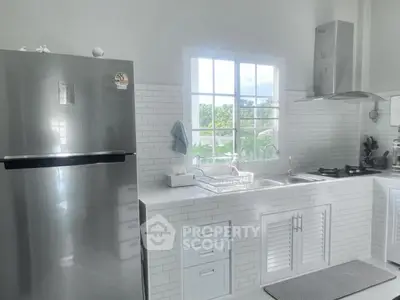 Modern kitchen with sleek stainless steel fridge and white cabinetry