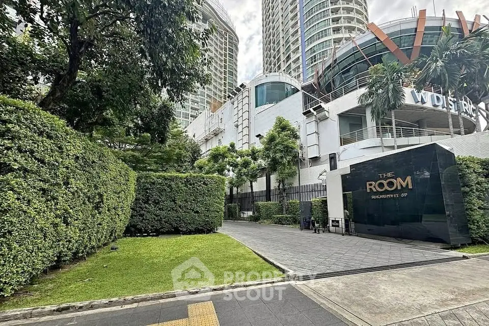 Luxurious condominium entrance with lush greenery and modern architecture in prime city location.