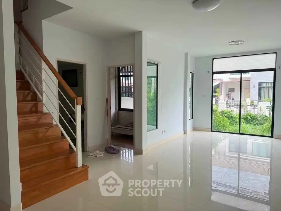 Spacious modern living room with large windows and wooden staircase