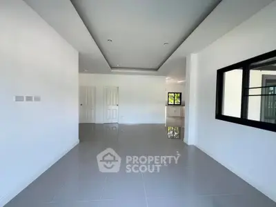 Spacious modern living room with sleek tile flooring and large windows for natural light.