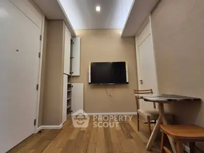 Modern living room with mounted TV and wooden flooring, featuring a cozy dining area.