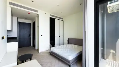 Modern studio apartment with sleek design, featuring a cozy bed, compact kitchenette, and ample storage space.