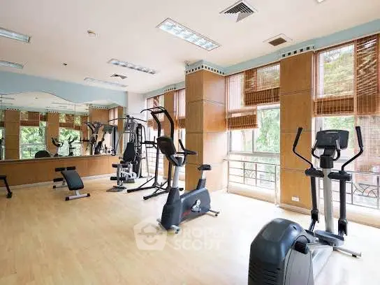 Spacious gym with modern equipment and large windows in a luxury residential building.