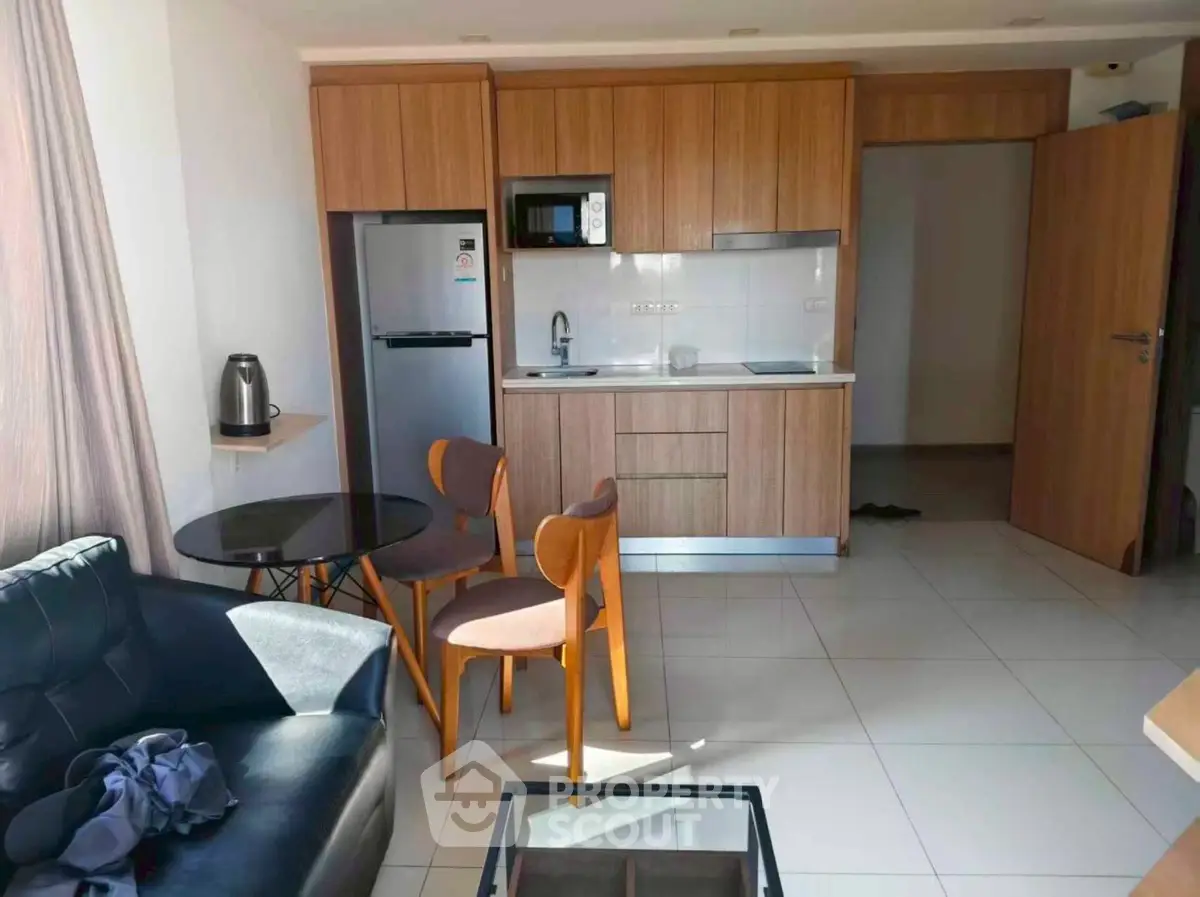 Modern apartment interior with compact kitchen and cozy dining area, featuring sleek wooden cabinetry and natural light.