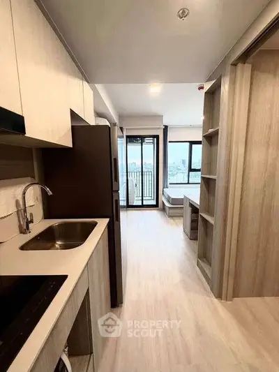 Modern apartment interior with open kitchen and living area leading to a balcony with city view.