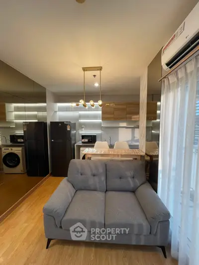 Modern living room with stylish sofa, open kitchen layout, and sleek appliances in a cozy apartment.