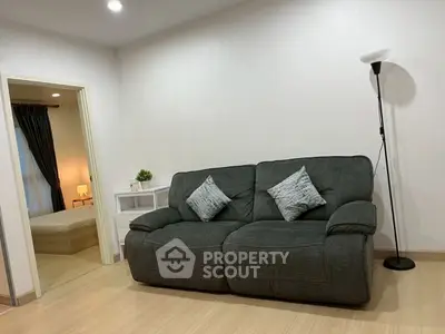 Modern living room with cozy sofa and stylish decor, leading to a serene bedroom retreat.