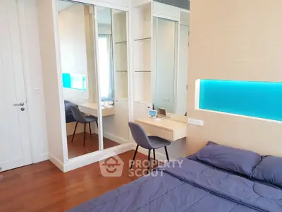 Modern bedroom with sleek design, mirrored closet, and cozy workspace