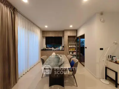 Modern dining area with elegant table and chairs, large window with curtains, and stylish lighting.