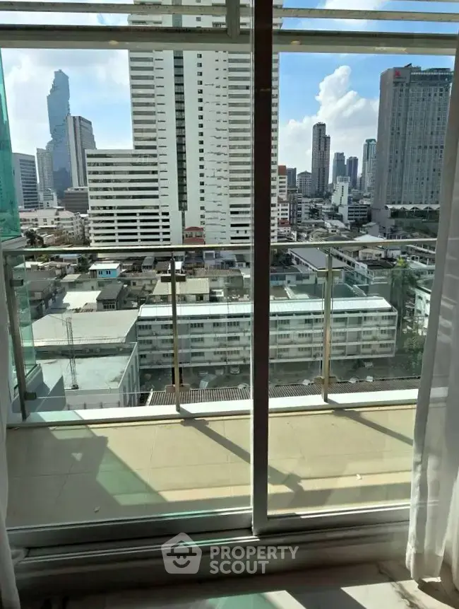 Stunning city view from high-rise apartment balcony with glass railing.