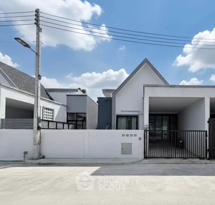 Modern minimalist house exterior with clean lines and bright facade under blue sky.