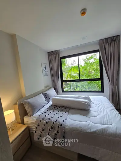 Cozy bedroom with large window and lush garden view, perfect for relaxation.