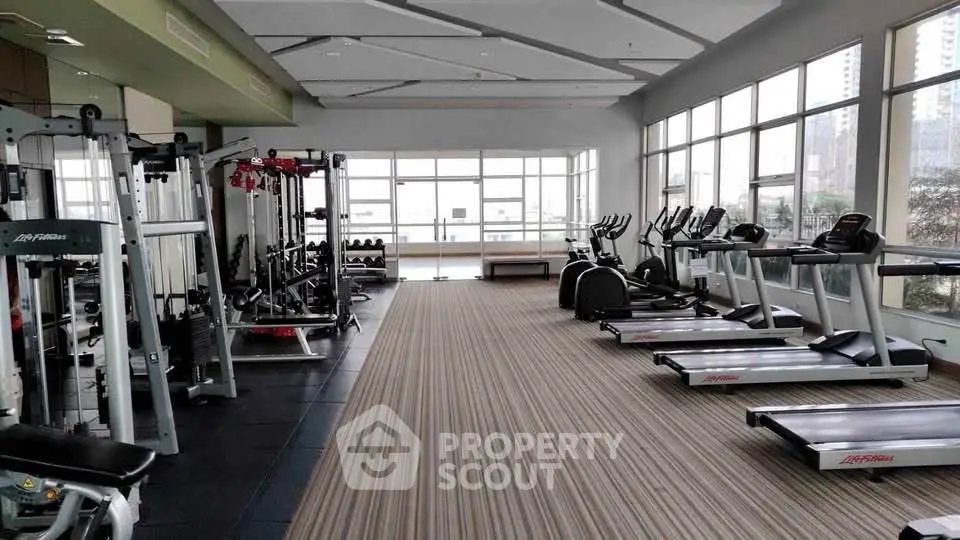 Spacious modern gym with state-of-the-art equipment and large windows for natural light.